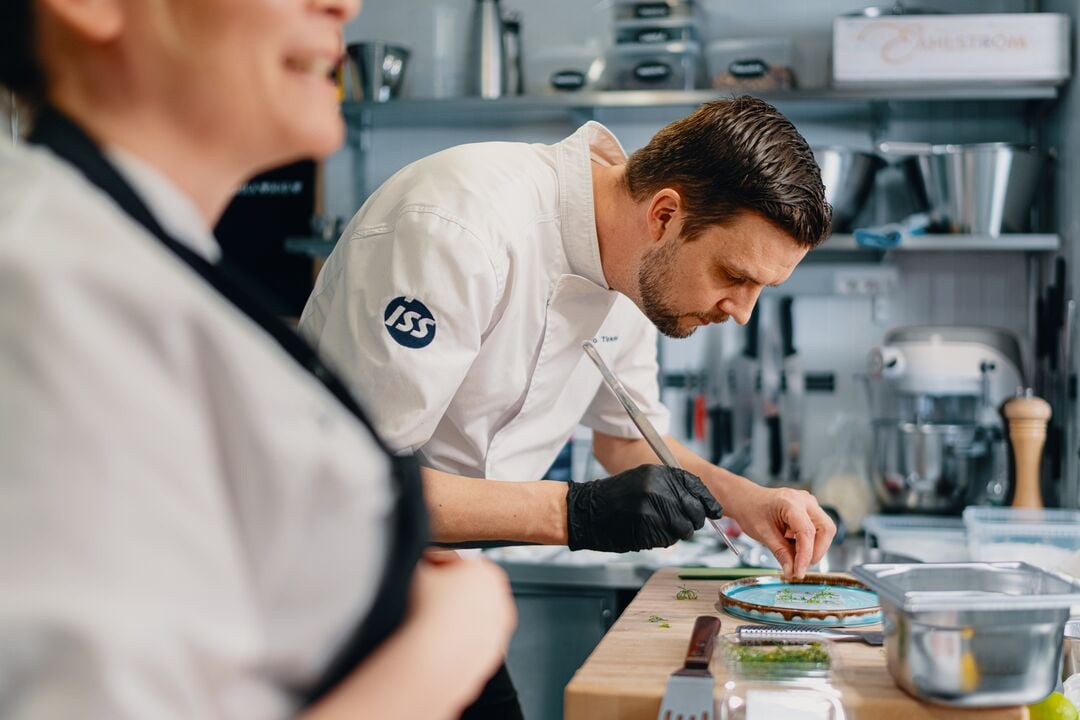 ISS kokk som jobber på kantine. Lager mat på profesjonell måte for kunder